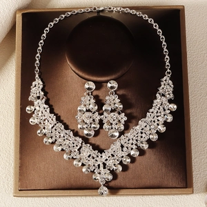 Detailed view of silver-tone bridal jewelry set with white rhinestones in a brown box