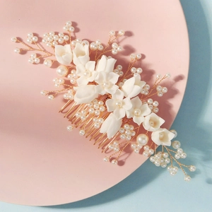Close-up of handmade bridal hair comb with white resin flowers and pearls on gold wire