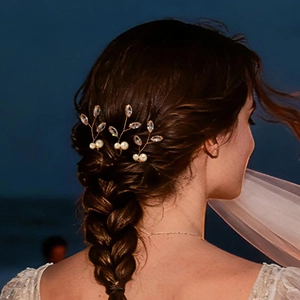 Dettaglio di forcine da sposa con perle e cristalli in un'acconciatura a treccia castana