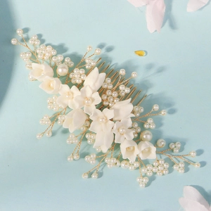 Close-up of white resin flower hair comb with pearls and gold wire for bridal styling