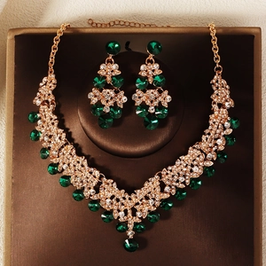 Detailed close-up of bridal jewelry set with emerald green crystals and floral accents