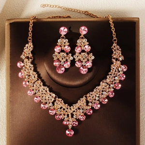 Detail of bridal jewelry set with pink rhinestones and gold-plated necklace earrings
