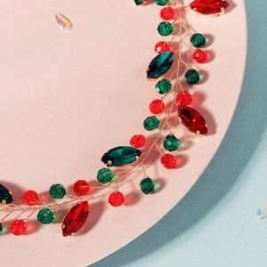 Détail d'un bandeau de Noël fait main avec des cristaux rouges et verts sur fil doré