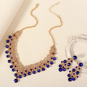 Vintage gold jewelry set with royal blue crystals and white rhinestones on warm background