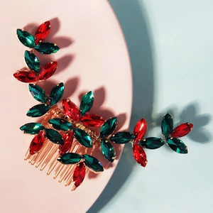 Macro shot of gold bridal hair comb with red and green crystal holly leaves decoration