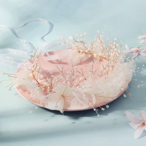 Dettaglio fascia sposa con petali in rete bianca e perle su uno sfondo azzurro