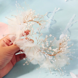 Vista dettagliata della fascia da sposa con filo dorato, perle bianche e petali in rete