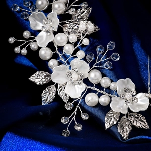 Détail macro de fleurs en acrylique blanc avec perles et cristaux sur peigne à cheveux argenté