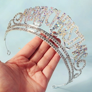 Détail macro d'une couronne argentée Merry Christmas avec strass tenue à la main