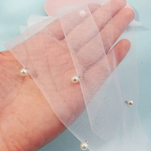Dettaglio del velo da sposa in rete bianca delicata con eleganti applicazioni di perle