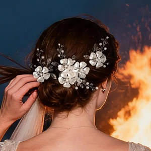 Detail of bridal hair pin set with acrylic petals and pearls on blue background