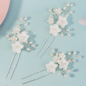 Detail of three U-shaped hairpins with white resin flowers and pearls for bridal hairstyles