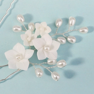 U-shaped bridal hair pin with white resin flowers and pearls on light blue background