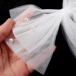 Dettaglio di un fiocco da sposa in rete bianca con perle eleganti e pizzo raffinato
