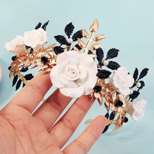 Close-up of handmade bridal crown featuring white clay roses and golden metal leaves