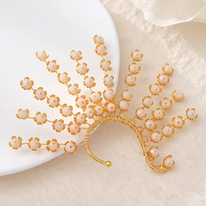 Forest style bridal crystal ear cuff with golden wire and pink frosted beads on a ceramic plate