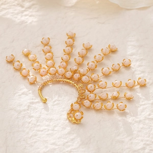 Close-up of golden wire woven bridal ear cuff with delicate pink crystal flower buds