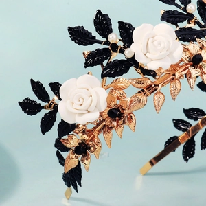 Detail of handmade bridal crown with white clay roses, black leaves and gold wire