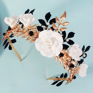 Handmade gold flower crown with white roses, black leaves and pearls on blue background