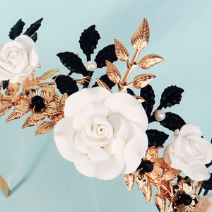 Macro detail of handmade bridal crown with white resin roses and golden metal leaves