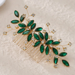Detail of handmade gold hair comb with emerald green rhinestones and leaf motifs