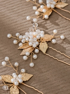 Détail d'épingles à cheveux dorées avec perles blanches et feuilles pour coiffures de mariée