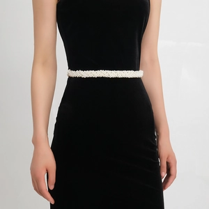 Close-up of elegant handmade white pearl bridal belt styled on a black velvet dress