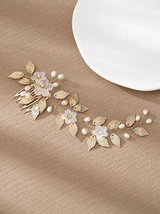 Détail d'un peigne à cheveux fait main avec feuilles dorées, perles et fleurs en résine