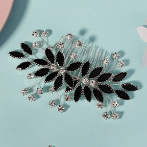 Macro shot of silver bridal hair comb featuring black leaves and sparkling rhinestones