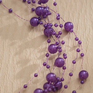 Macro view of purple faux pearl bridal headband with beaded design and metallic luster