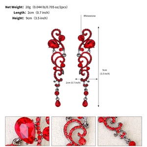 Detail showing red rhinestone tassel earrings with vintage floral scroll metalwork