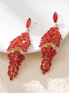 Detail view of red rhinestone bridal earrings with marquise-cut gems on a golden base