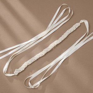 Elegant hand-woven pearl waist chain with white satin ribbons on textured background