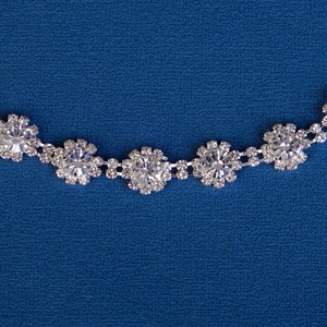 Vue détaillée d'une chaîne à fleurs argentées avec cristaux brillants sur fond bleu