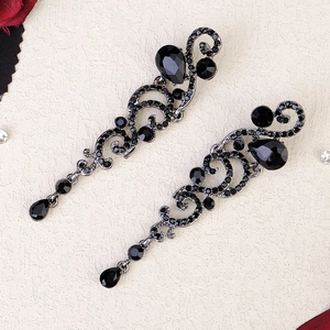 Close-up of vintage silver teardrop earrings with black rhinestones and filigree detail