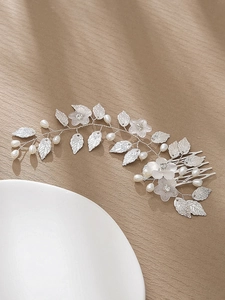 Détail d'un peigne à cheveux argenté avec fleurs, perles délicates et feuilles mates