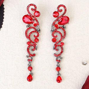 Macro detail of silver vintage teardrop earrings with red rhinestones and vine patterns