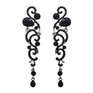 Macro detail of vintage silver-tone drop earrings with black rhinestones and scroll patterns