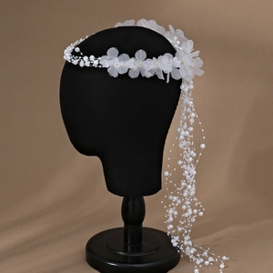 Detailed macro shot of white fabric flowers and beaded pearl tassels on bridal headband