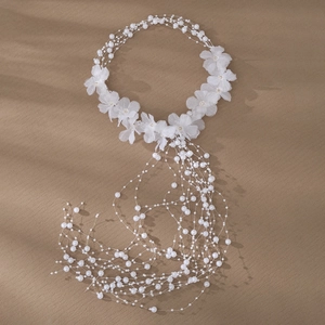 Close-up of white tulle flowers and long pearl tassels on bridal hair accessory