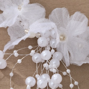 Close-up of handmade bridal headband featuring white lace petals and pearl bead tassels