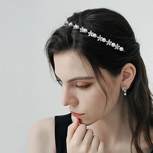 Detail of high-crown pearl headband and matching earrings with silver flower crystals