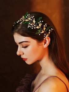 Macro detail of bridal headband with golden metal leaves, green foliage and white pearls