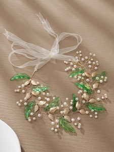 Detail of bridal headband with golden branches, green leaves and white organza ribbon