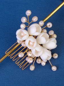 Macro shot of handmade floral hair comb with white lily petals, pearls and gold wire