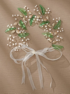 Detail of bridal hairband with green acrylic leaves, pearls and gold wire design