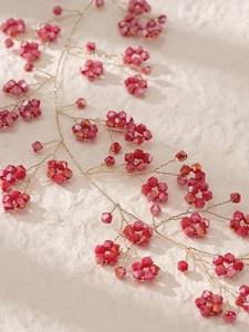 Détail macro d'une vigne de cheveux de mariée avec perles rouges et fil doré