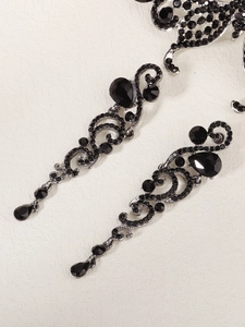 Détail de boucles d'oreilles vintage noires avec strass sombres et pompons