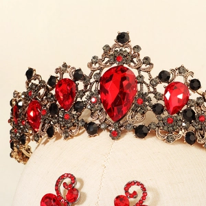 Macro shot of Baroque crown and earrings featuring red crystals and ornate bronze metalwork