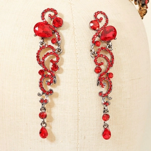 Detail of red crystal drop earrings with vintage black vine patterns and tassels